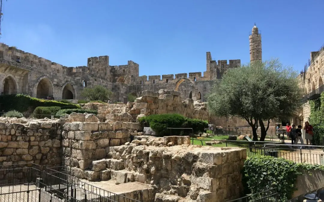 a group of people walking around a stone building